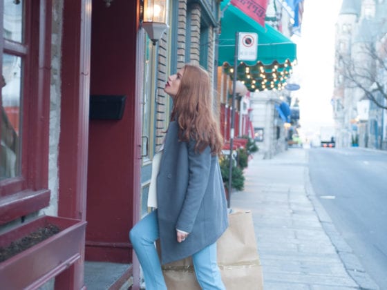 A woman in a jacket and boots walking into a cafe from the road