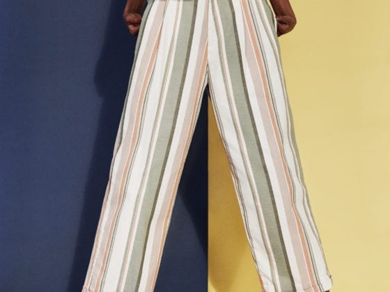 An image of the lower half of a black woman in stripped pants and sandals