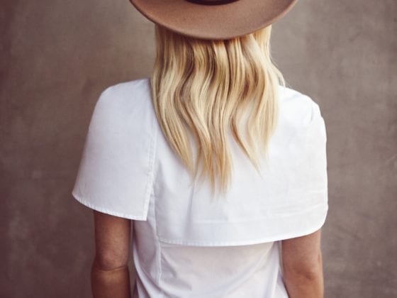 A woman in a white tee with a fedora hat facing with her back the camera