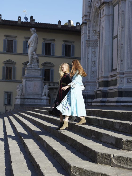 Two women walking down the stairs in dresses and their hair blowing