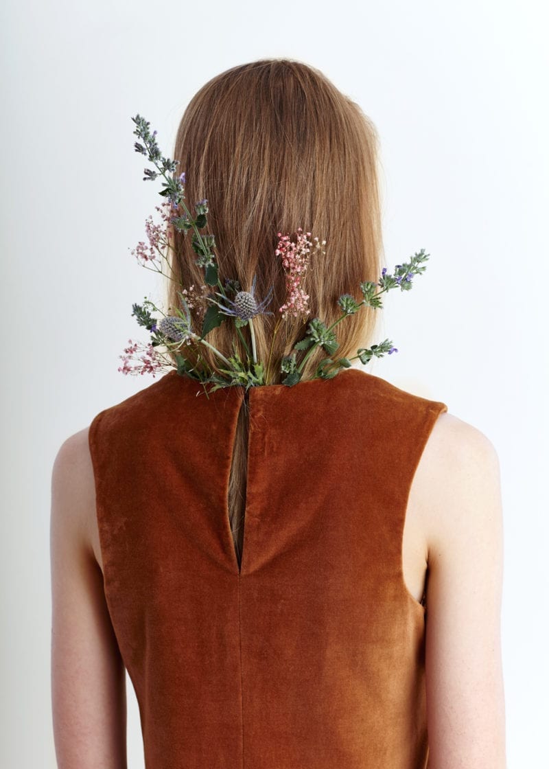 A picture of the back of woman with flowers tucked in at the neckline of her dress