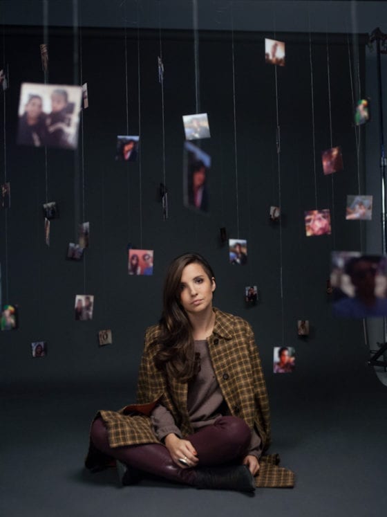 A woman sitting on the floor with pictures of people hanging around her