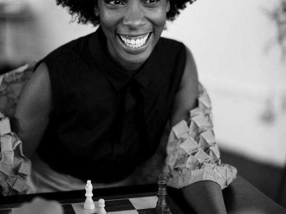 A smiling woman seated at a chess table