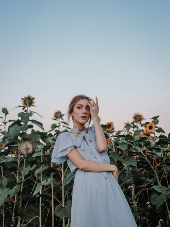 A picture of a girl in a dress in a field of sunflowers