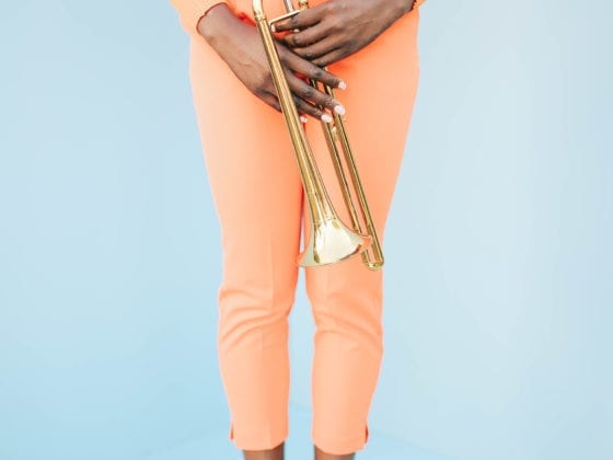 A photo of a woman's lower torso as she holds a saxophone in front of her body