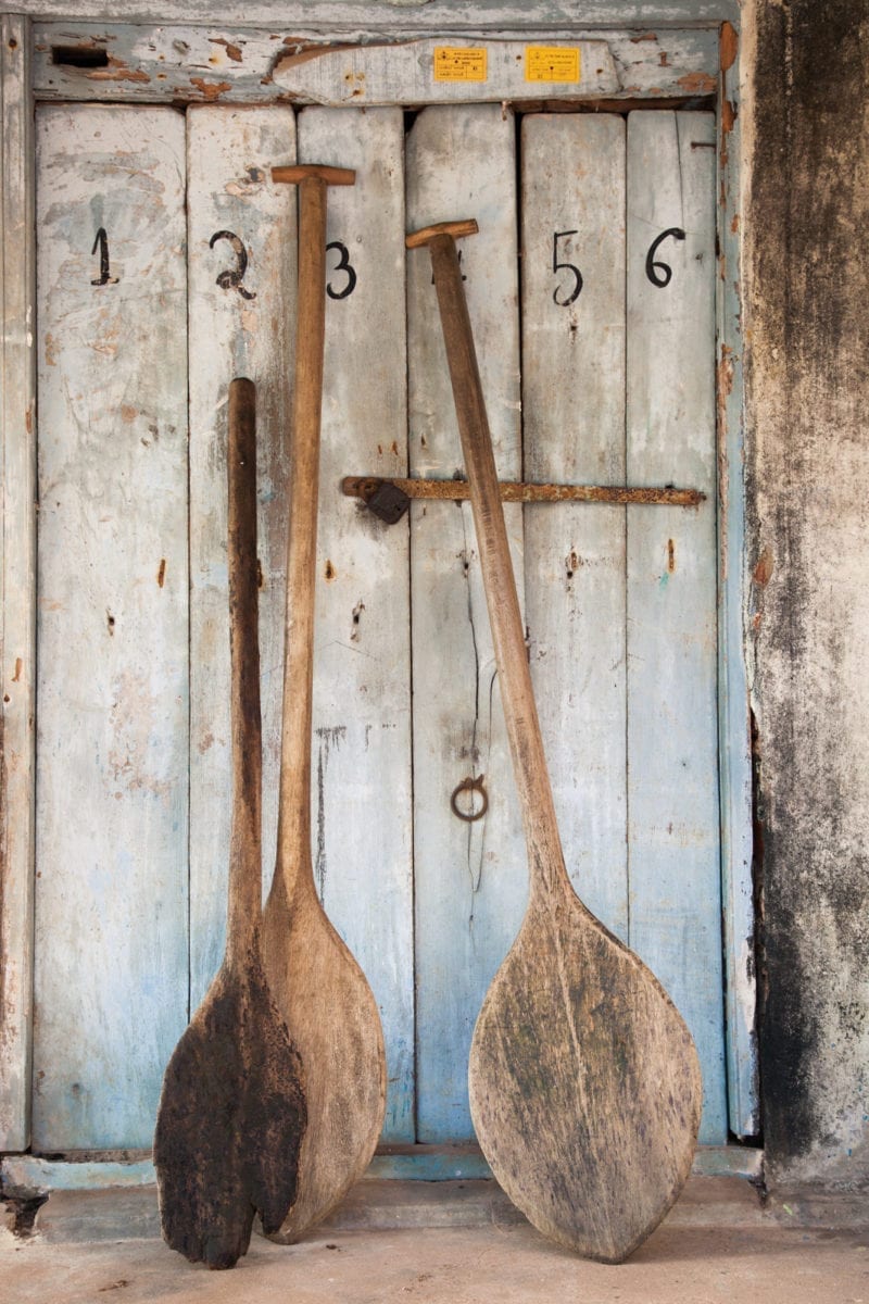 Three paddles leaned against an old wooden cabinet