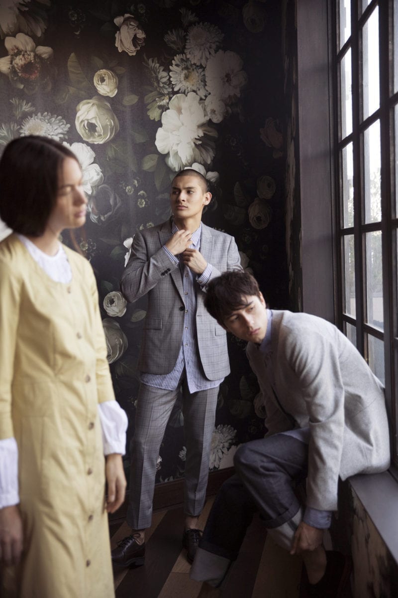 A group of young adults in professional attire seated by a window sill