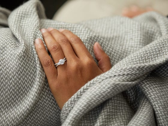 A woman's ring hand under a blanket