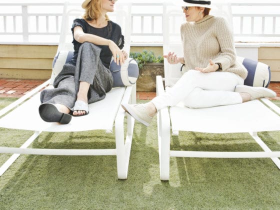A mom and her daughter looking at each other as they sit on patio chairs
