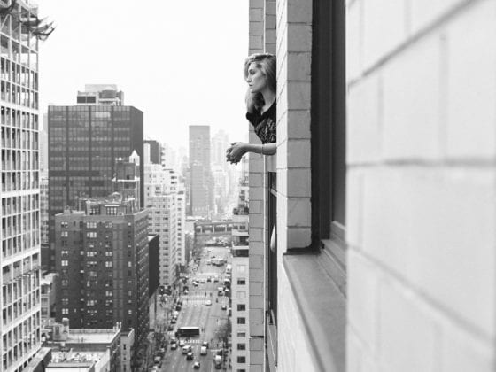 A woman looking out her window above a cityscape