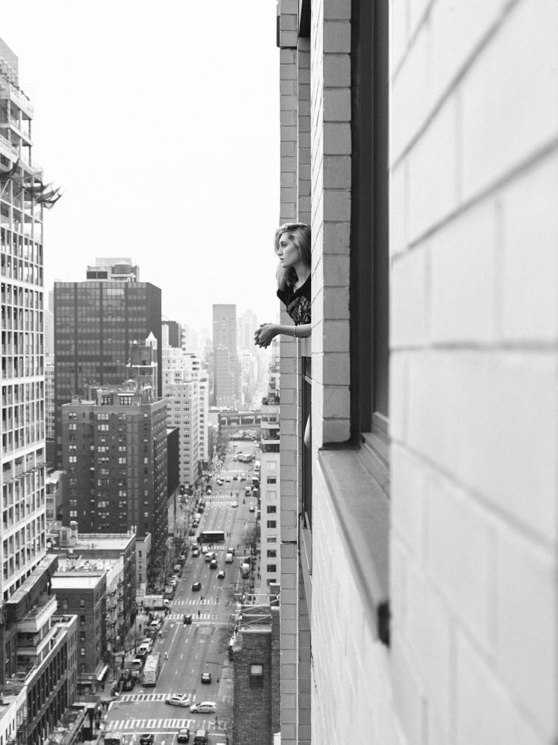 A woman looking out her window above a cityscape