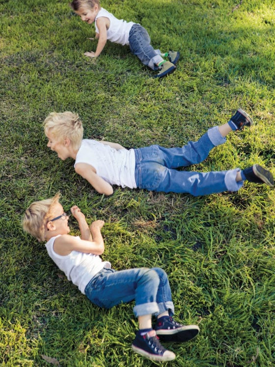 A picture of three little boys rolling in the grass