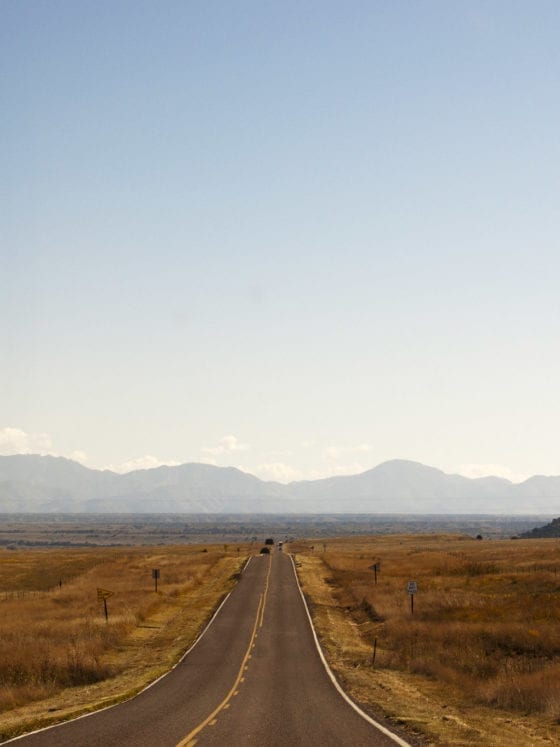A picture of a road through a plains with mountains in the background