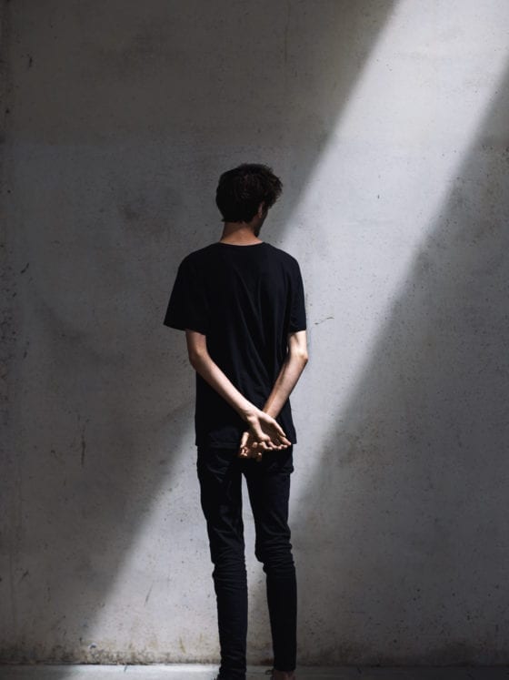 A picture of the back of a man who is facing a wall