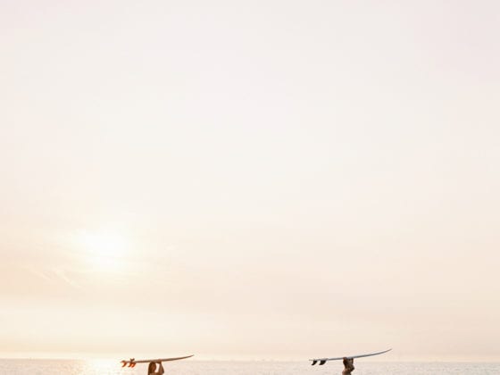 Two surfers walking with their boards held above their heads