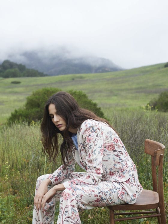A woman sitting on a chair outside in a hilly area that is overcast