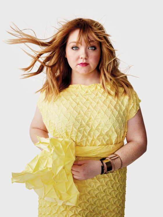 A woman in a yellow dress standing as the wind blows her hair