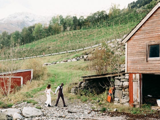 A couple holding hands as they walk near a barn