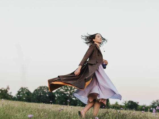 A woman in a dress and jacket dancing in a field