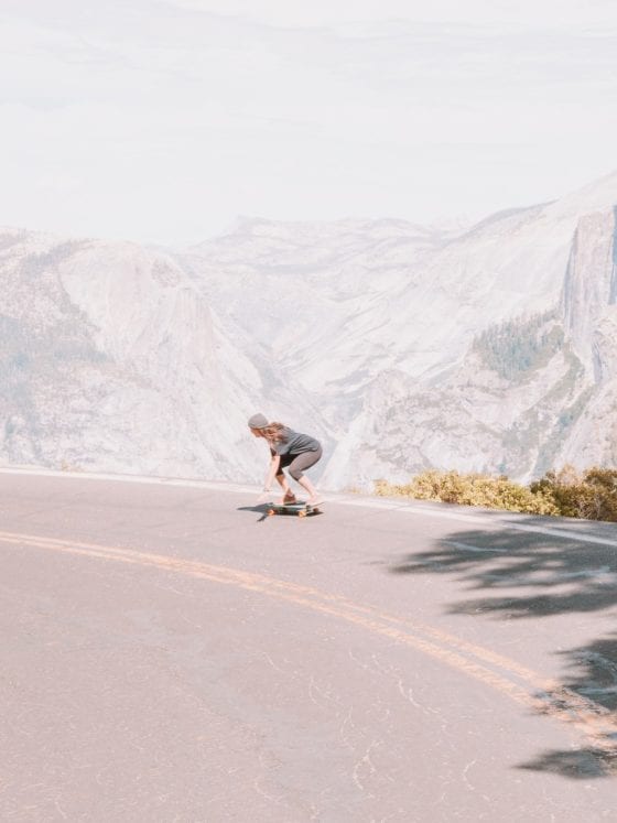A woman skateboarding down a road near a mountain