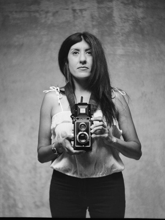 A black and white photo of a woman holding a camera