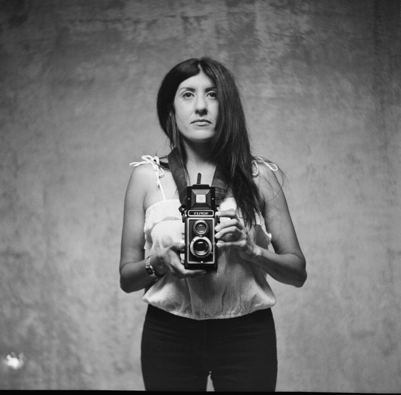 A black and white photo of a woman holding a camera