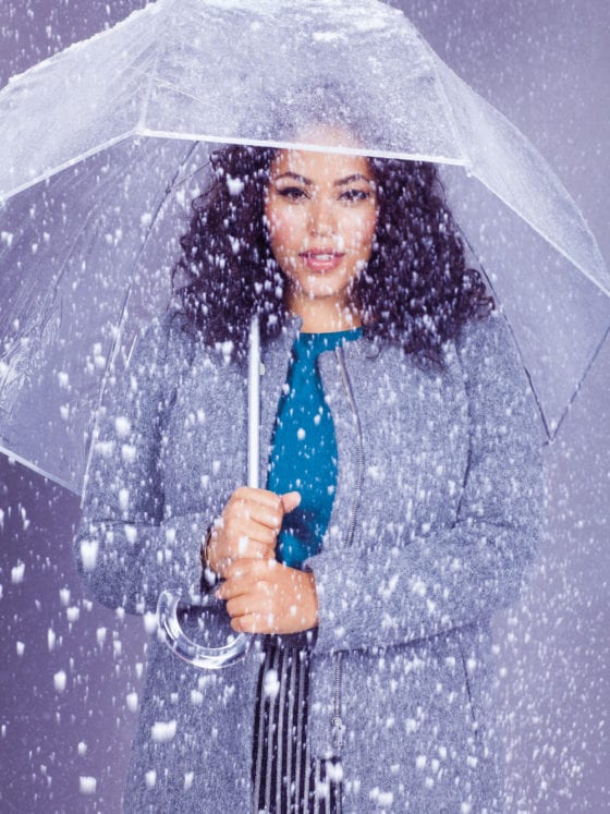 A woman holding an umbrella under snowfall