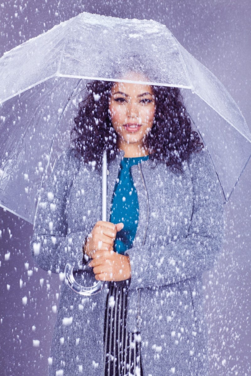 A woman holding an umbrella under snowfall