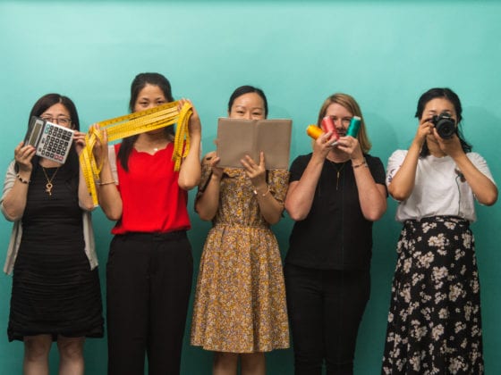Five women holding up items th cover their faces
