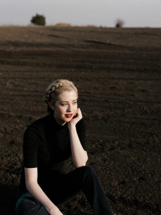 A woman wearing all black sitting in a field