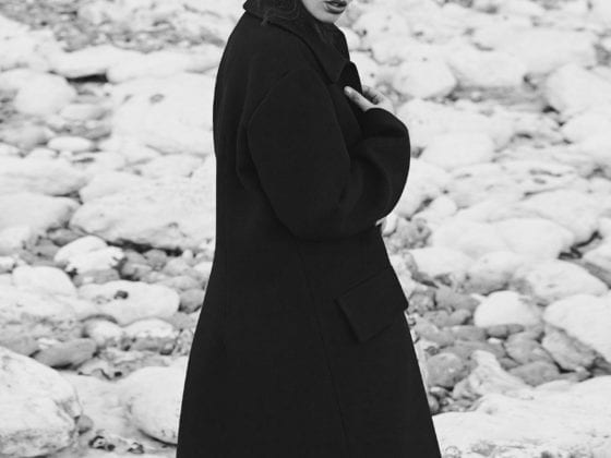 A woman in a black overcoat standing outside in a winter season