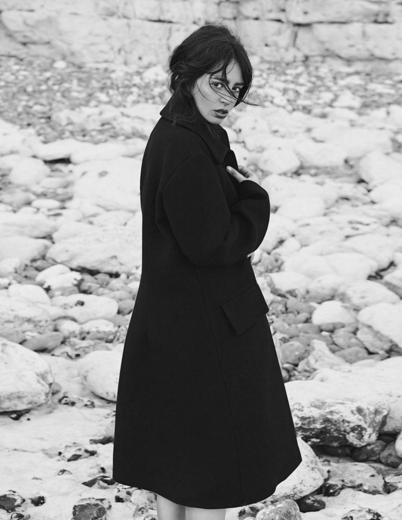 A woman in a black overcoat standing outside in a winter season