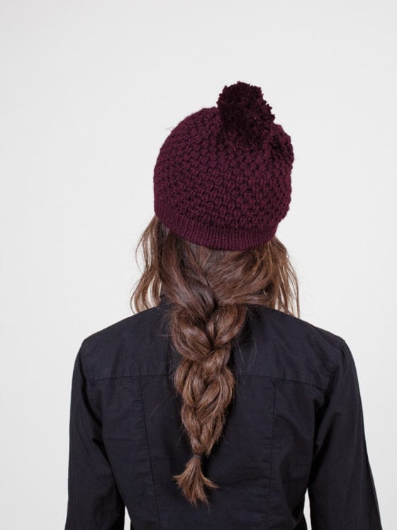 The back of a woman wearing a beanie with her hair in a braid