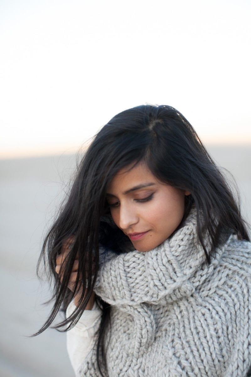 A woman with a thick scarf sweater looking downward
