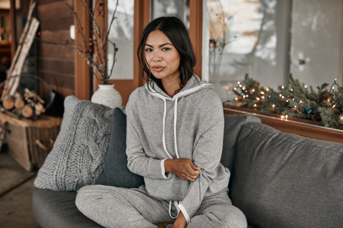 A woman in a hoodie jumpsuit on a couch