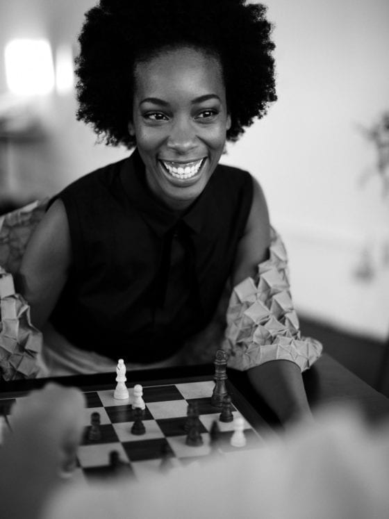 A smiling woman leaning forward over a game of chess