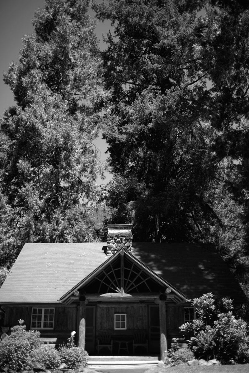 A black and white photo of a house in a residential area with trees
