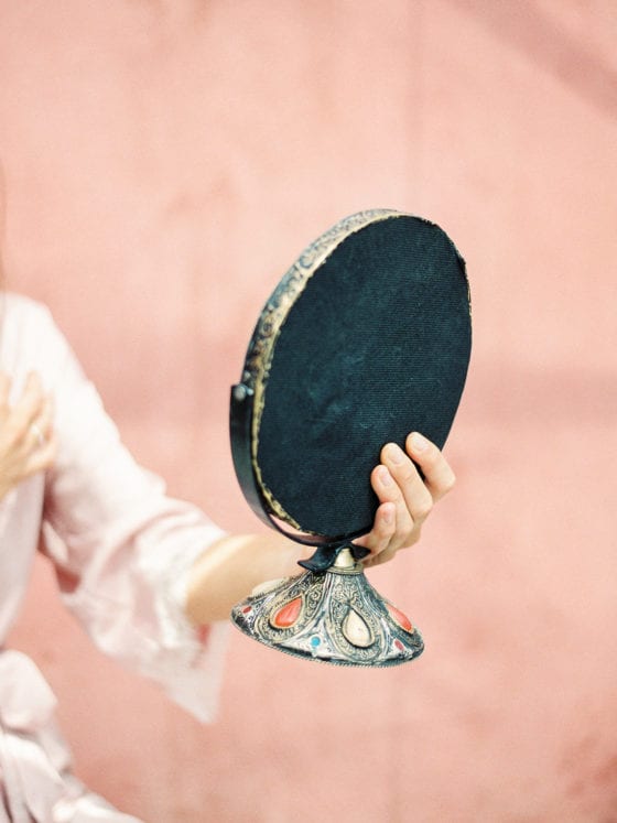 A woman's hand holding a oval-shaped vanity mirror