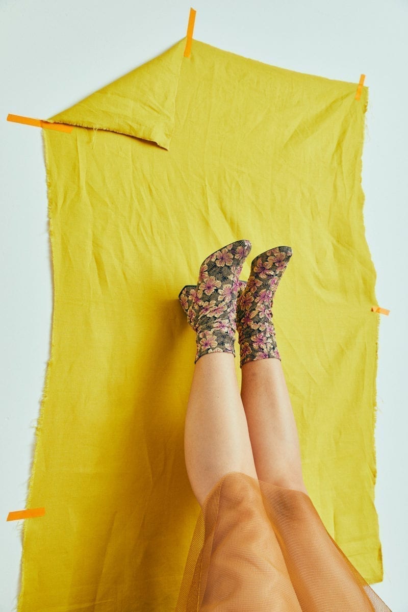 A woman's feet leaning against fabric that is tapped to the wall