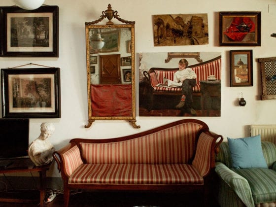 A picture of a living room with a few sofas and a wall covered with art